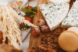 Plateau de bois garni de fromages entames, de pain et de raisin