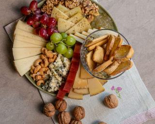 Plateau de bois garni de fromages entames, de pain et de raisin