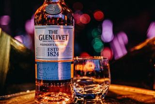 Verre de whisky ambré posé sur un comptoir en bois