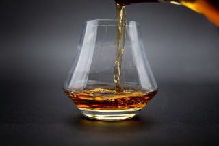 Verre de whisky ambré posé sur un comptoir en bois